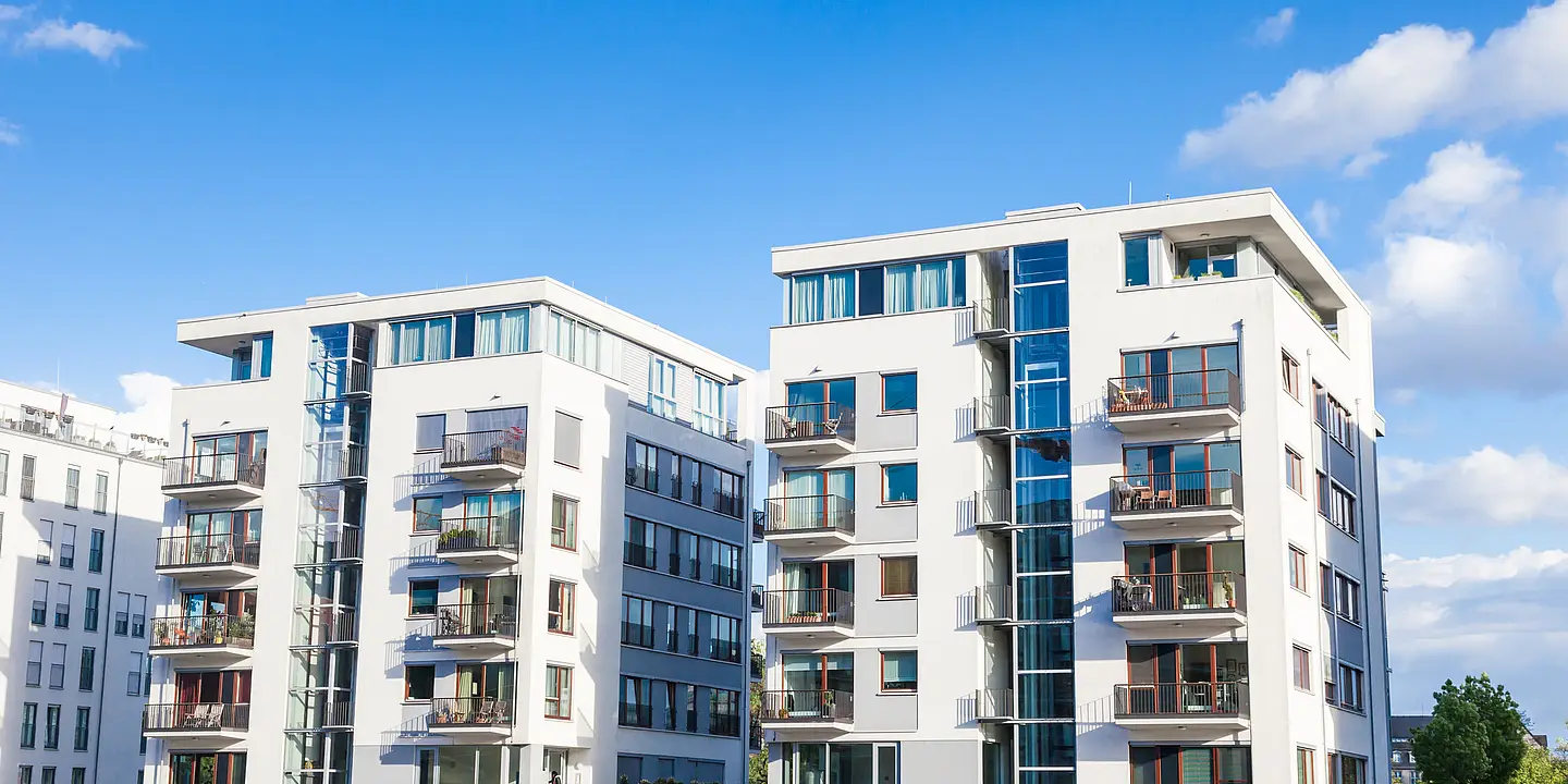 Moderne Mehrfamilienhäuser mit Balkonen vor blauem Himmel